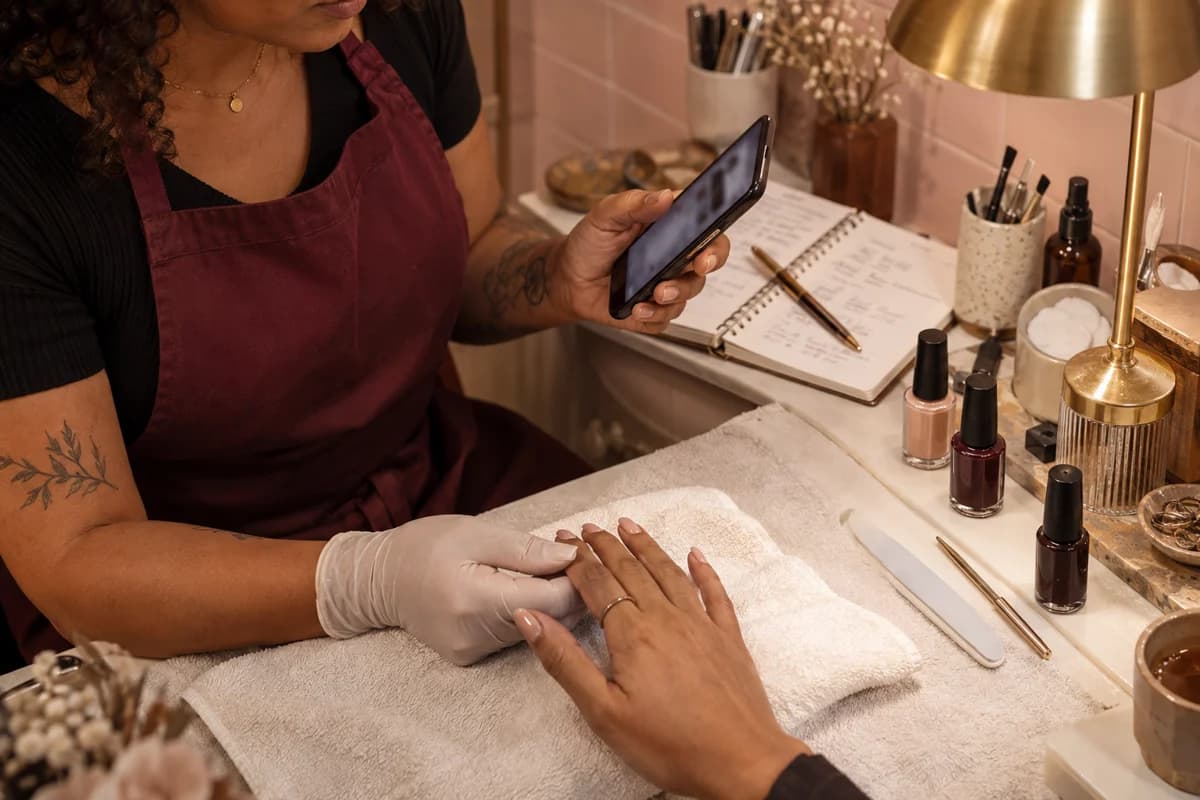 Cena ilustrativa de uma manicure interrompendo o atendimento para olhar o celular, ao lado do caderno de horários